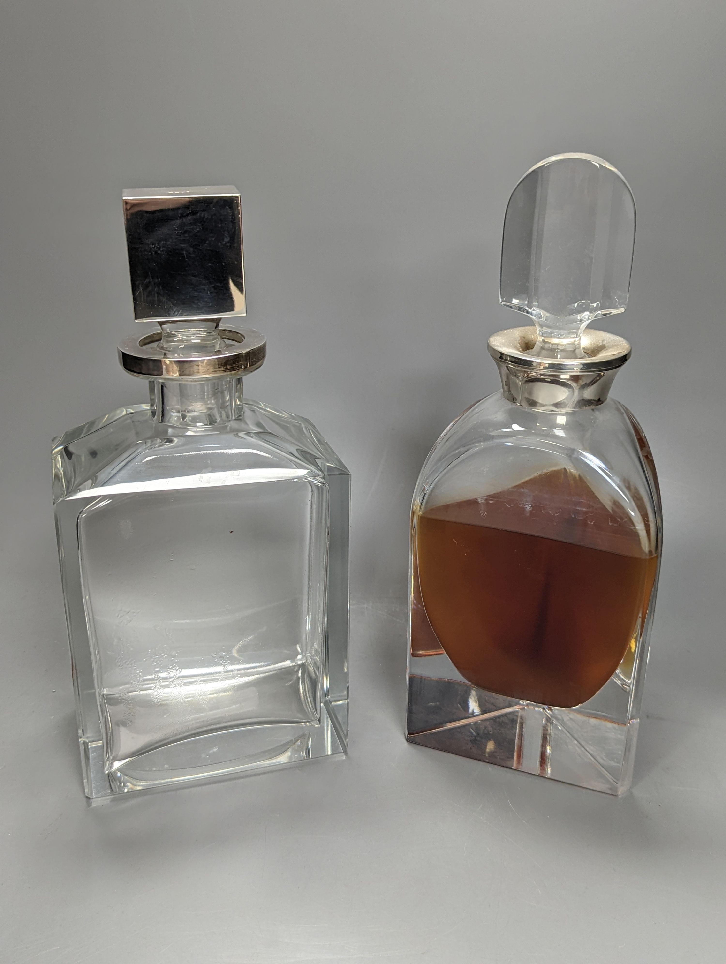 A silver mounted triangular glass decanter and a similar oblong spirit decanter, both with silver mounts and stoppers, tallest 27cm